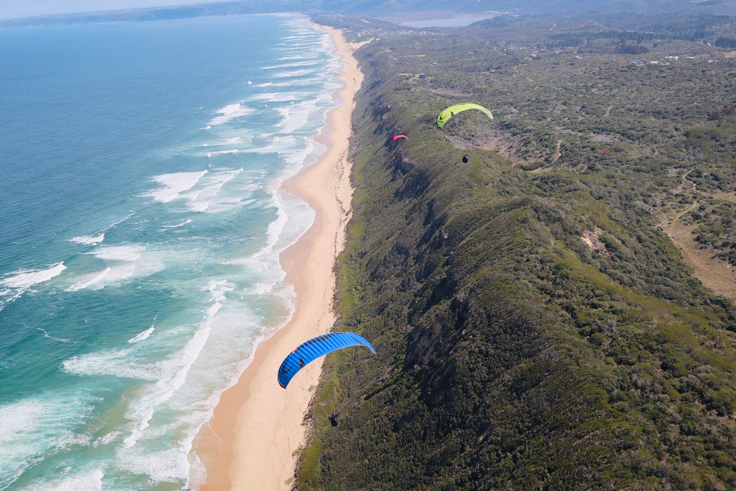 Two paraglider's soaring the coastline in Wilderness South Africa with epic beach and sea view