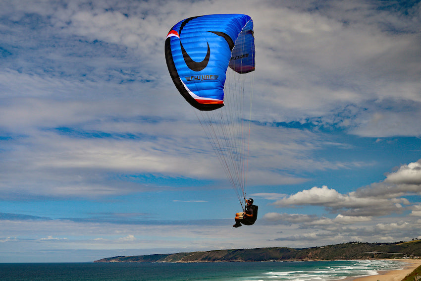 Person learning to paraglide with a beach and sea background